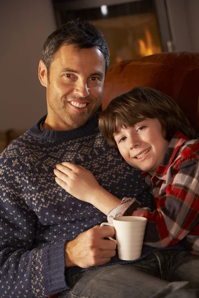 Ojciec i syn relaksując się przy gorącej pić oglądanie telewizji przez przytulne dziennika f — Zdjęcie stockowe