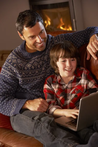 Vader en zoon laptopcomputer gebruikt door gezellige open haard — Stockfoto