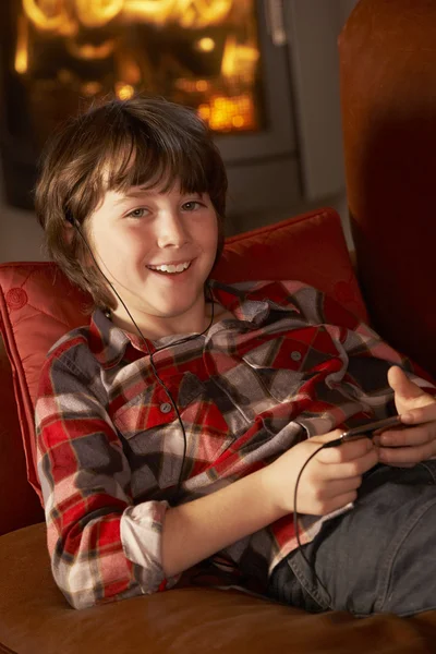 Jeune garçon se détendre avec lecteur MP3 par feu de journal Cosy — Photo