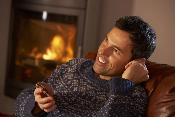 Mann mittleren Alters benutzt MP3-Player am gemütlichen Kaminfeuer — Stockfoto