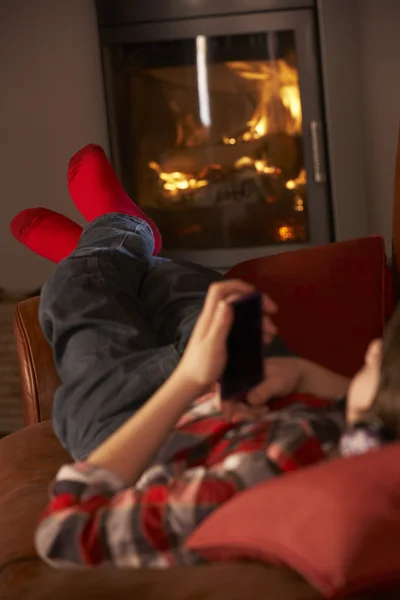 Молодой парень расслабляется с MP3-плеером, уютный огонь журнала — стоковое фото