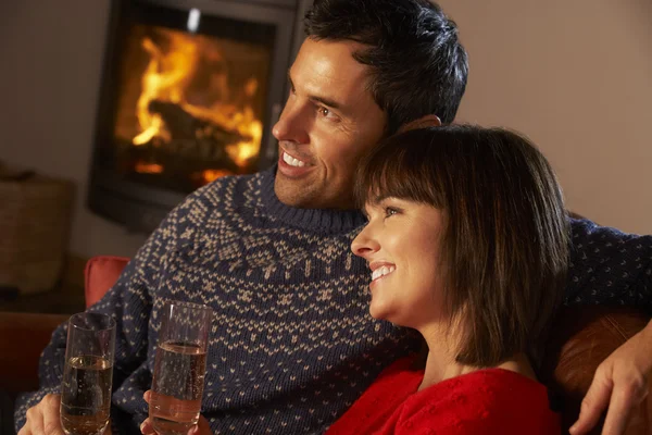 Middle Aged Couple Sitting Sofa By Cosy Log Fire With Glass Of C — Stock Photo, Image
