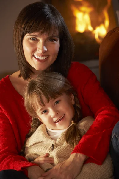 Madre e hija relajándose en el sofá por el fuego de registro acogedor —  Fotos de Stock