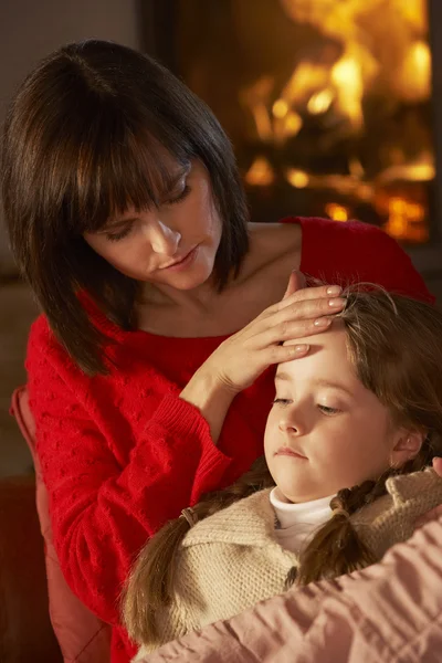 Madre confortante malato figlia su divano da accogliente log fuoco — Foto Stock