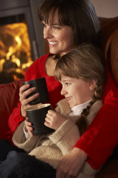 Madre e hija relajándose con bebida caliente viendo la televisión por acogedor —  Fotos de Stock
