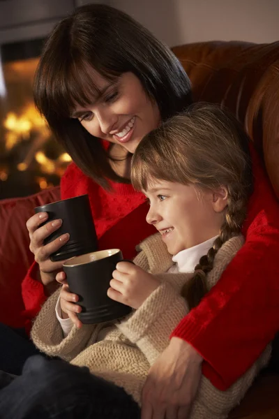 Madre e hija relajándose con bebida caliente viendo la televisión por acogedor —  Fotos de Stock