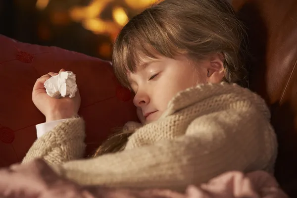 Chory dziewczynka z zimną odpoczynku na kanapie przy przytulnym kominkiem — Zdjęcie stockowe
