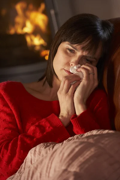 Zieke vrouw met koude rusten op sofa door gezellige open haard — Stockfoto