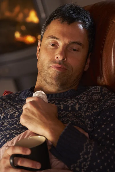 Kranker Mann mit Erkältung ruht auf Sofa am gemütlichen Kaminfeuer — Stockfoto