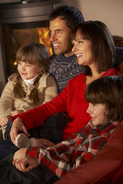 Familia relajante ver la televisión por acogedor registro de fuego —  Fotos de Stock