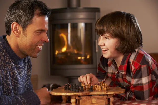 Ojciec i syn gra w szachy przez przytulnym kominkiem — Zdjęcie stockowe