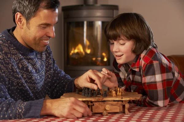 Padre e hijo jugando ajedrez por fuego de registro acogedor — Foto de Stock