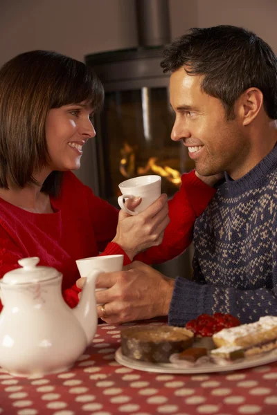 Paar genießt Tee und Kuchen am gemütlichen Kaminfeuer — Stockfoto