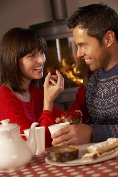 Paar genießt Tee und Kuchen am gemütlichen Kaminfeuer — Stockfoto