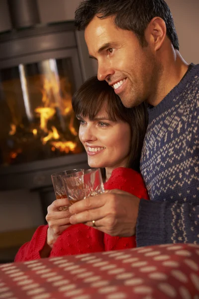 居心地の良い暖炉でテレビを見ながらソファに座っている中年夫婦 — ストック写真