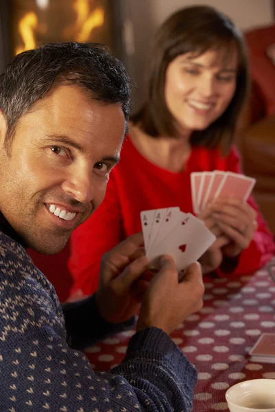 Pareja jugando a las cartas por acogedor fuego de registro — Foto de Stock