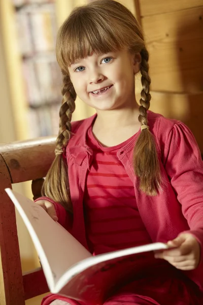Kitap okuma ahşap sandalye üzerinde oturan genç kız — Stok fotoğraf