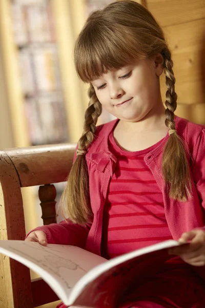 Menina sentada no livro de leitura de assento de madeira — Fotografia de Stock