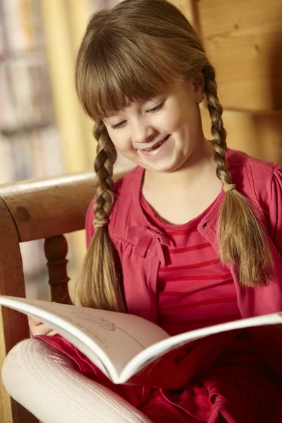 Dívka sedící na dřevěným sedákem čtení knihy — Stock fotografie