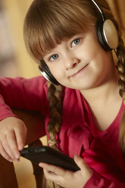 Junges Mädchen sitzt auf Holzsitz und hört MP3-Player — Stockfoto