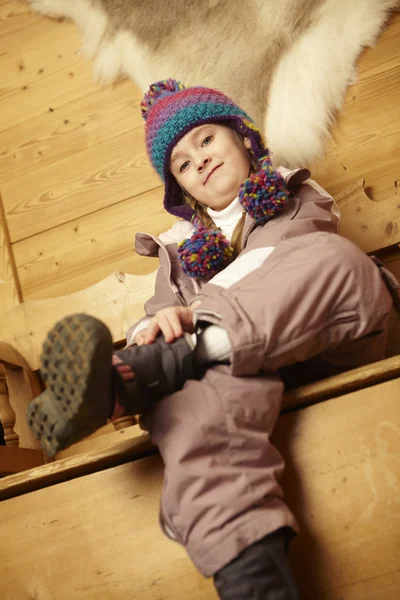年轻的女孩坐在木制座椅穿上保暖户外衣 — 图库照片