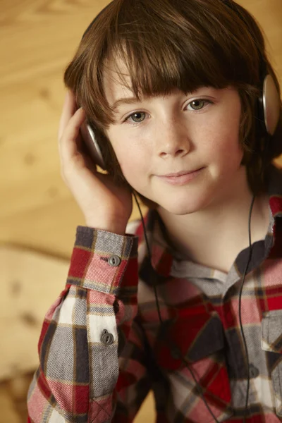 Молодий хлопець сидить на дерев'яному сидінні прослуховування MP3 плеєр — стокове фото