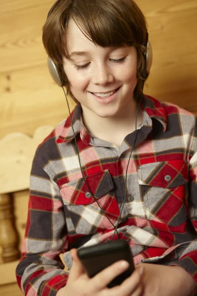 Menino jovem sentado na escuta de assento de madeira para MP3 Player — Fotografia de Stock