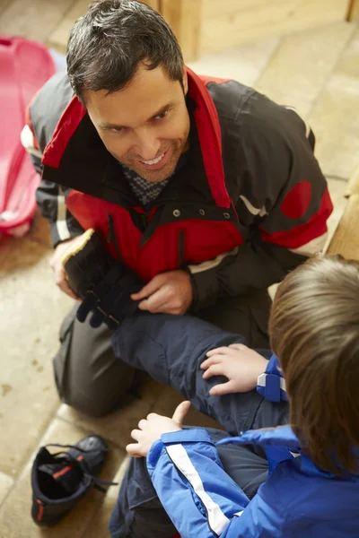 Padre ayudando a su hijo a ponerse ropa caliente al aire libre y botas —  Fotos de Stock