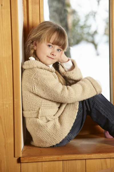 雪に覆われた景色眺めて窓の棚に座っている若い女の子 — ストック写真