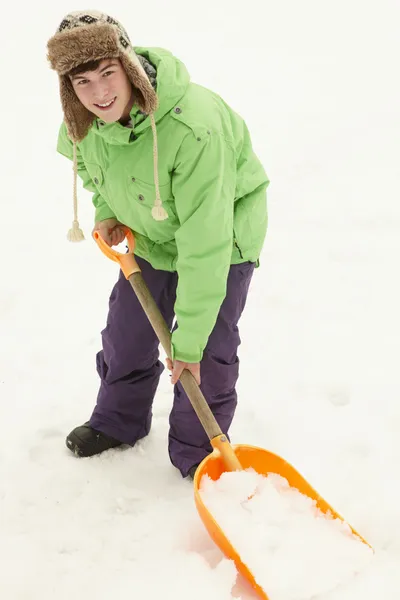 Adolescente menino pá neve do caminho — Fotografia de Stock