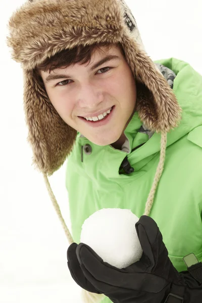 Adolescente menino segurando bola de neve vestindo chapéu de pele — Fotografia de Stock