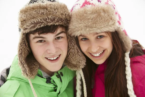 Retrato de casal adolescente na neve vestindo chapéus de pele — Fotografia de Stock