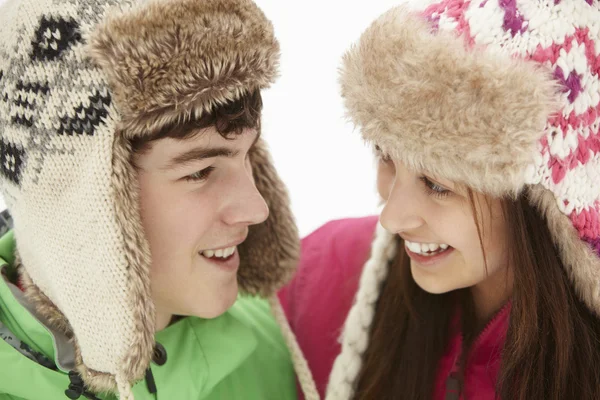 Couple adolescent dans la neige portant des chapeaux de fourrure — Photo