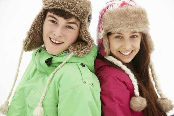 Retrato de casal adolescente na neve vestindo chapéus de pele — Fotografia de Stock