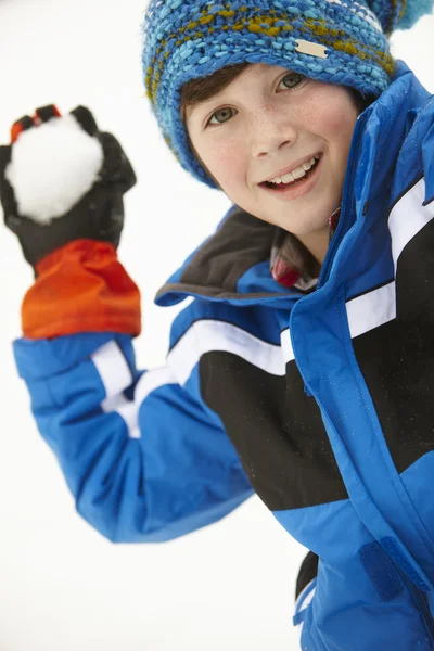 羊毛質の帽子を着て雪だるまをスローするように約若い男の子 — ストック写真