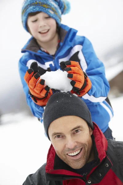 Мальчик собирается уронить снежок на отцовскую голову — стоковое фото