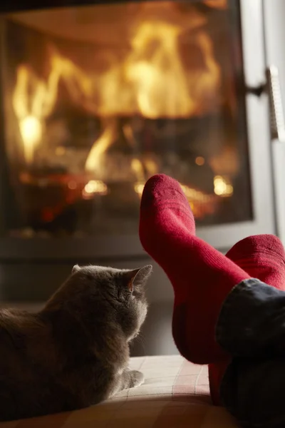 Gros plan des pieds de Mans se détendre par feu de bois confortable avec chat — Photo