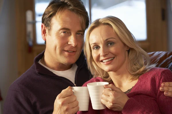 Middle Aged Couple Sitting On Sofa With Hot Drinks — Stock Photo, Image