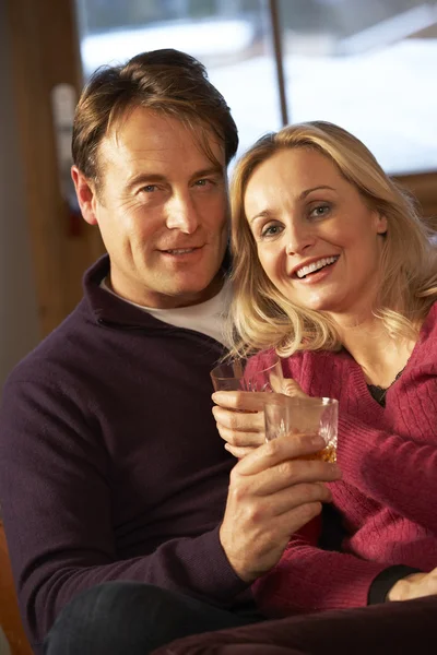 Mellersta åldern paret sitter på soffan med glas whisky — Stockfoto