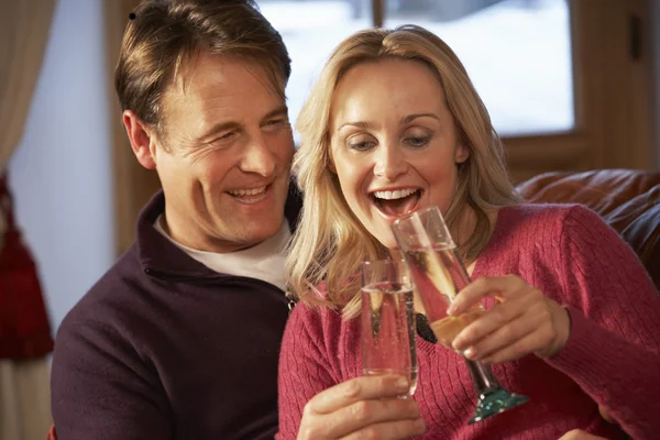 Mellersta åldern paret sitter på soffan med glas champagne — Stockfoto