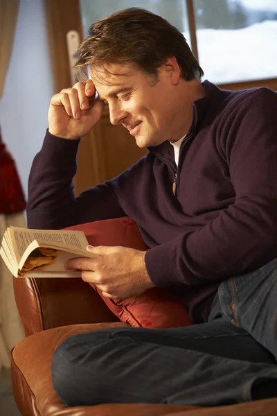 Mann mittleren Alters entspannt sich mit Buch auf Sofa — Stockfoto