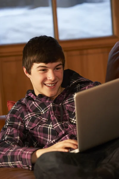 十几岁的男孩休闲沙发用的笔记本电脑上 — 图库照片