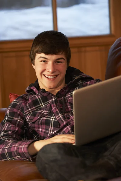Adolescente menino relaxante no sofá com laptop — Fotografia de Stock
