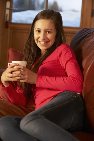Adolescente chica relajante en sofá con bebida caliente —  Fotos de Stock