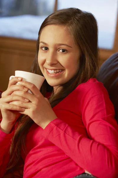 Adolescente menina relaxante no sofá com bebida quente — Fotografia de Stock