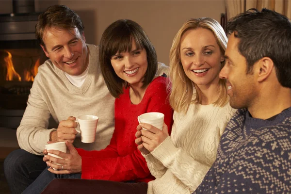 Grupo de casais de meia-idade sentados no sofá com bebidas quentes Tal — Fotografia de Stock
