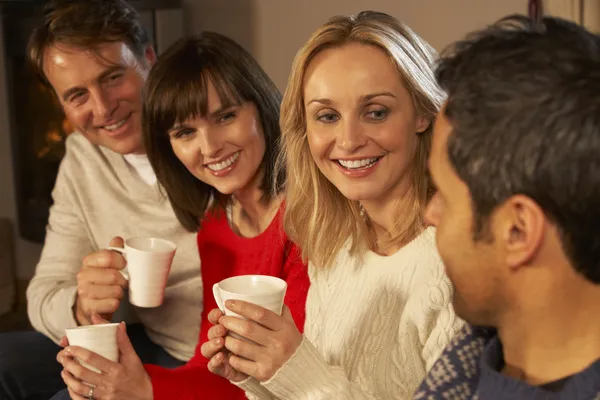Gruppe von Paaren mittleren Alters sitzt mit heißen Getränken auf dem Sofa — Stockfoto