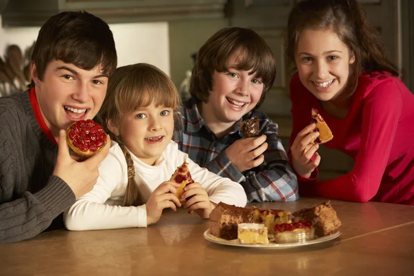 台所でケーキの皿を楽しむ子どもたちのグループ — ストック写真
