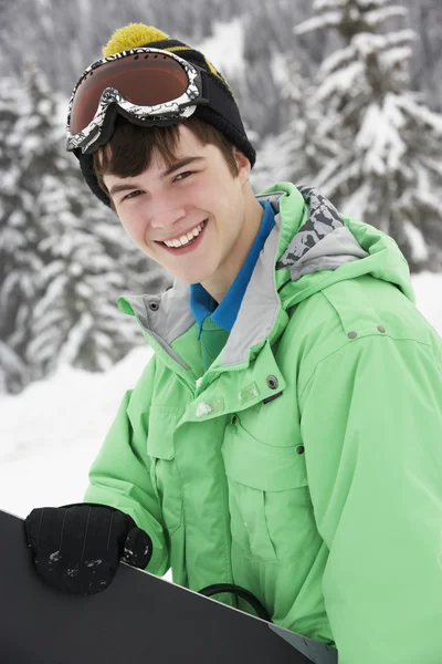 Tonårspojke med snowboard på skidsemester i bergen — Stockfoto