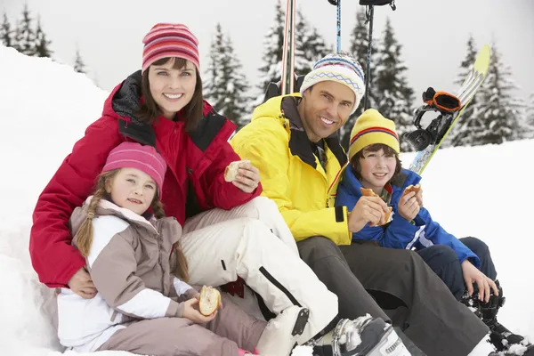 Famiglia che mangia panino in vacanza sugli sci in montagna — Foto Stock